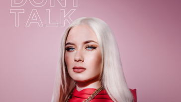Single cover artwork for "We Don't Talk" by Wiktoria, which sees her standing in a red top in front of a pink background