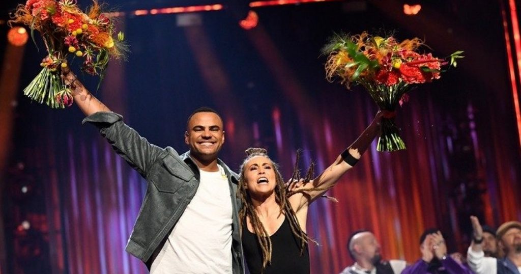 Mohombi and Mariette hugging whilst holding their flowers up high in celebration of their win on the Melodifestivalen 2020 stage