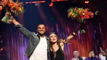 Mohombi and Mariette hugging whilst holding their flowers up high in celebration of their win on the Melodifestivalen 2020 stage
