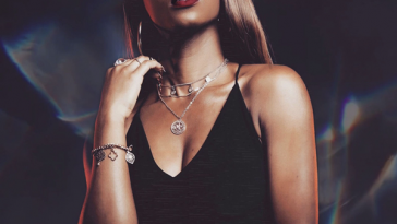 Relley C on the cover of her "We've All Been There" EP with straight hair and wearing a black bra-top paired with a low-hanging necklace and matching bracelet.