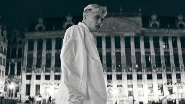 Loïc Nottet in the music video for "Mr/Mme" wearing a white oversized shirt looking off to the right located in Brussels.