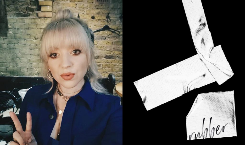 Leah McFall on the left, wearing a blue shirt-jacket with her highlighted blonde and her fingers up in a peace side, whilst the single artwork cover for "Rubber" is on the right which is black with paper strips.