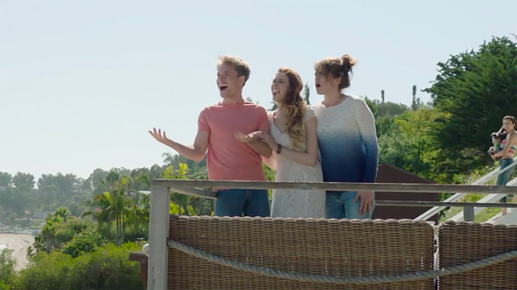 Still from the Tell Me I Love You film which sees Ben, Ally, and Melanie (played by Sam Clark, Paulina Cerrilla, and Kaniehttio Horn, respectively) standing on a balcony overlooking Malibu.