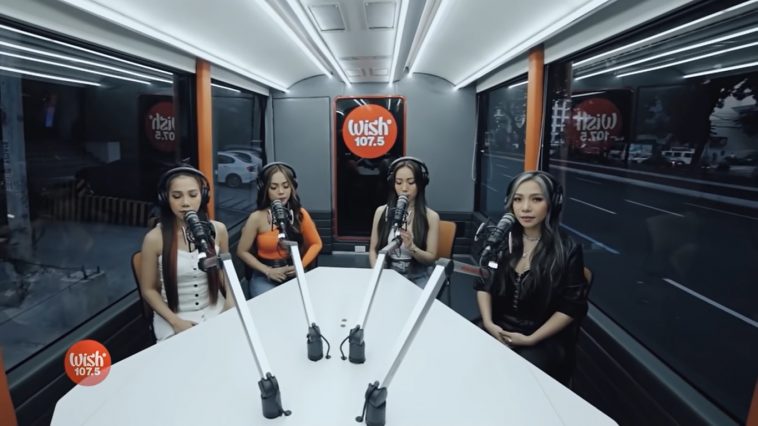 4th Impact sitting around a table with microphones inside the Wish 107.5 Bus singing their song "K(NO)W MORE".