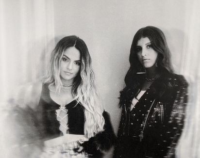 Black and white press photo for "Slow Motion" which sees JoJo on the left and Lindsey Lomis on the right, both are wearing black.