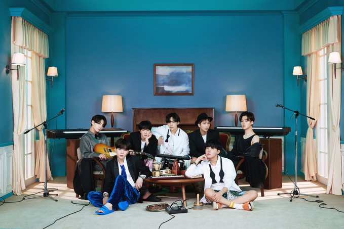 BTS gathered in a room with instruments for the concept cover of their new album BE