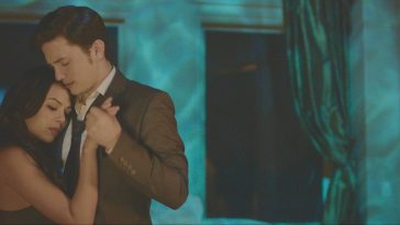 Film still from Until We Meet Again, which sees Jackson Rathbone in a suit hugging Janel Parrish as if they're dancing. The room is bathed in a soft teal light.
