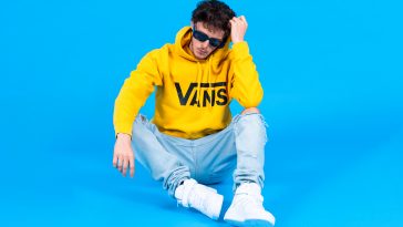 Scott the Pisces in a promotional image for "Summer '22" which sees him wearing a bright yellow Vans hoodie, light blue jeans, and white hi-top trainers, with a bright blue background.
