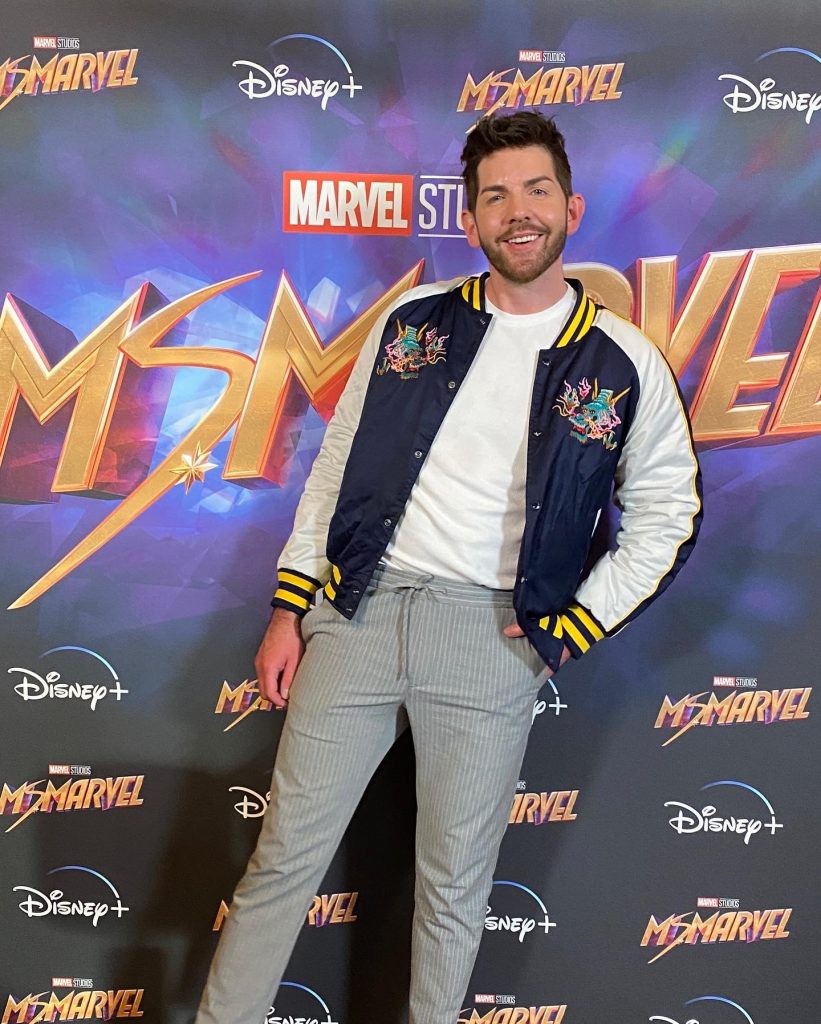 Scott McGlynn wearing a blue dragon Superdry jacket with a white tee and grey trousers at the Disney+ Screening premiere of Ms. Marvel