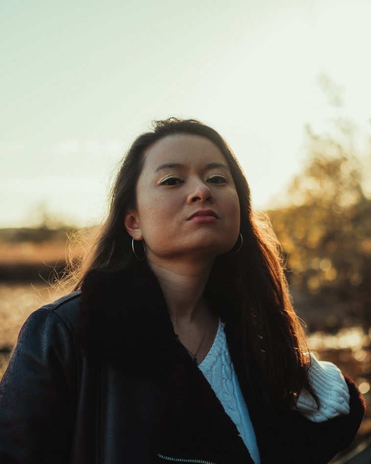 Promotional photo for "Closer" which sees Laura Loh in the countryside basking in the sun whilst wearing a white tee and a black striped jacket.