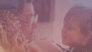 Album artwork of "Revolving Shores" by Graffiti Welfare which shows a faded filtered image of his late grandmother holding a young kid who is his older brother. His older brother is holding a seashell up to his grandmother's ear.