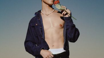 Single cover artwork of "Break" by Luke Markinson which sees the singer shirtless wearing a denim jacket over black jeans which sit just below the white waistband of his Calvin Klein's. He's holding a rose up to his face, and there is a blue-orange ombre background.