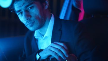 Promo photo of Evan de Roeper in lavender lighting wearing a suit.