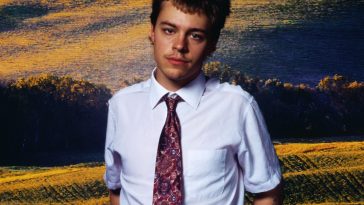 Promotional photo for "Superstar" which sees Christian Leave wearing a white shirt and a patterned light-red tie, backed by a countryside landscape.