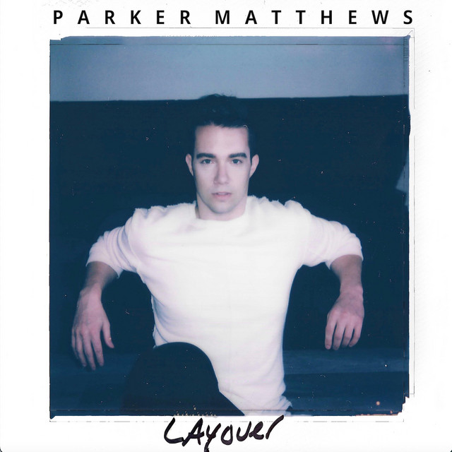 Single cover artwork for "Layover" which sees a square photo of Parker Matthews wearing a white t-shirt and black jeans sitting down with his arms resting behind him, framed by a black border with the artist name at the top and the title at the bottom.