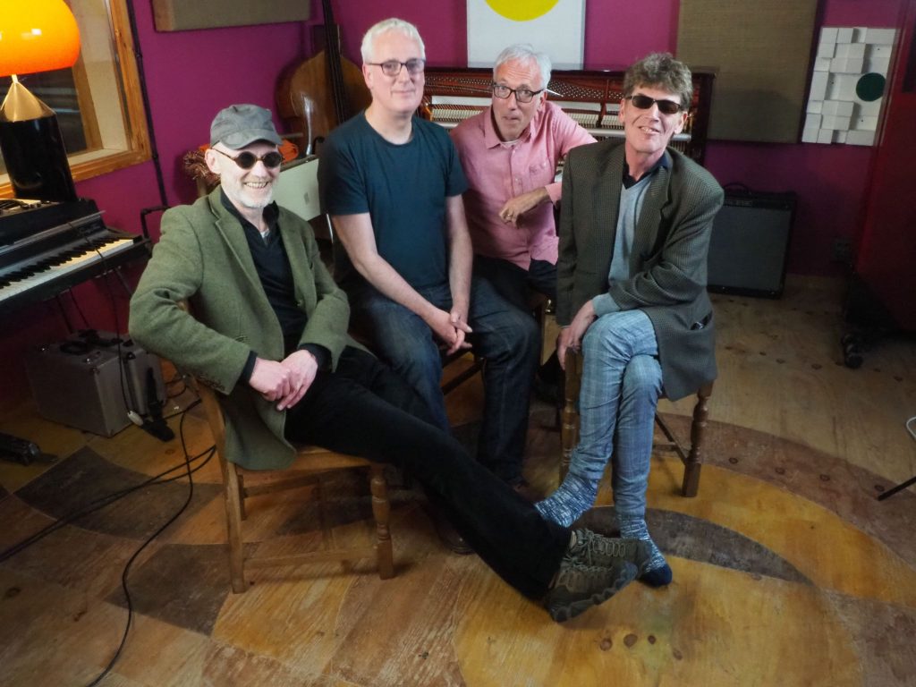 Promotional photo for "Their Mistake" which sees Otherish sitting in a studio. They are four middle to old age men all smiling at the camera.