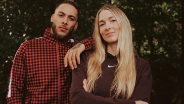 Promotional photo for "Clouds" which sees Delleile Ankrah standing to the left of Marie Dahlstrom in front of a tall hedge, with Delleile's arm on Marie's shoulder. Delleile is wearing a red and black tracksuit, with his hair tied back into a manbun, whilst Marie is wearing a burgundy Nike sweater with her blonde hair cascading down past her shoulders, with her arms crossed.
