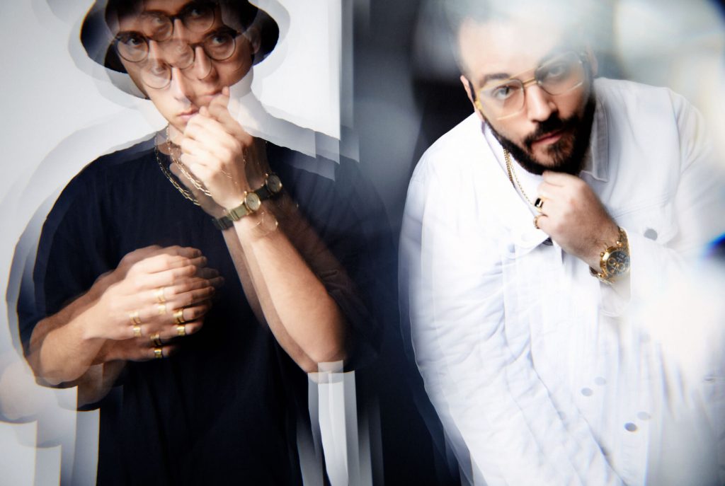 Promotional photo for "Thank Myself" which sees a slightly distorted blurred image of two men with their left hands on their chins, with Capo Corleone on the right wearing a white sweater, and Kuba Wiecek on the right wearing a black t-shirt, a black fedora hat, and a black watch.
