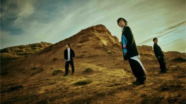 In promotion of their North American Tour, RADWIMPS pose on the edge of a grassy hill top, with the rock band donning black clothes and the blue sky cutting the scenery in half.
