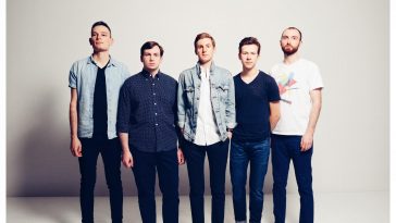 Promotional photo for "Desert Bloom" which sees Earthquake Lights posing in a professional photo studio, where all five band members are lined up, all wearing jeans and shirts.