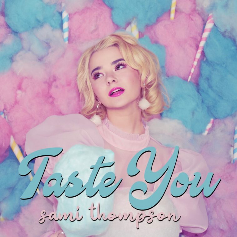 Official single cover artwork for "Taste You" which sees a head-shot of Sami Thompson against a blue and pink blobs of cotton candy which spreads across her cotton candy jacket. Her head is tilted to the left with her blonde hair in slight wavy curls.