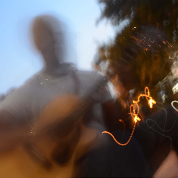 Single cover artwork for "Lately." which sees Tre. Charles with his guitar in a park, with the blue sky behind him, and he is majorly blurred out.