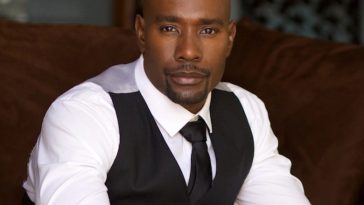 Promotional photo for Indie Night Film Festival which sees Morris Chestnut wearing a white shirt under a black tie and a grey waistcoat. He is sitting on a brown couch.
