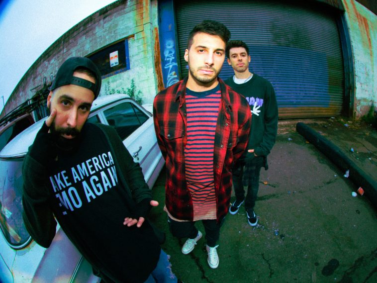 Promotional photo for "Bleach (Move On)" which sees Cash Cash standing outside a garage with a white car behind them towards the left, whilst the garage door is towards the right, also behind them. They're wearing trendy everyday wear and posing somewhat for the camera.