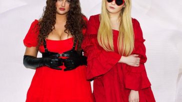 Single cover artwork for "Woman's Intuition", which sees Lily Lane and Sophomore (Abigail Breslin) wearing red dresses, standing next to each other. Sophomore is wearing shades with her blonde hair going past her shoulders, with her right hand held on to her left-arm's elbow. Lily Lane is standing on the left of Sophomore, wearing black gloves and she has long curly brown hair that also goes past her shoulders.