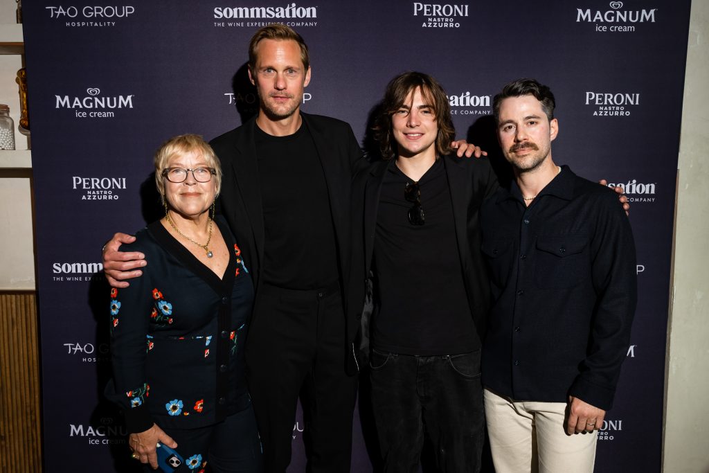 Sarah Green, Alexander Skarsgård, Shea Pritchard, and Karl Hartman posing in front of a sponsor backdrop in promotion of their film "Eric Larue"