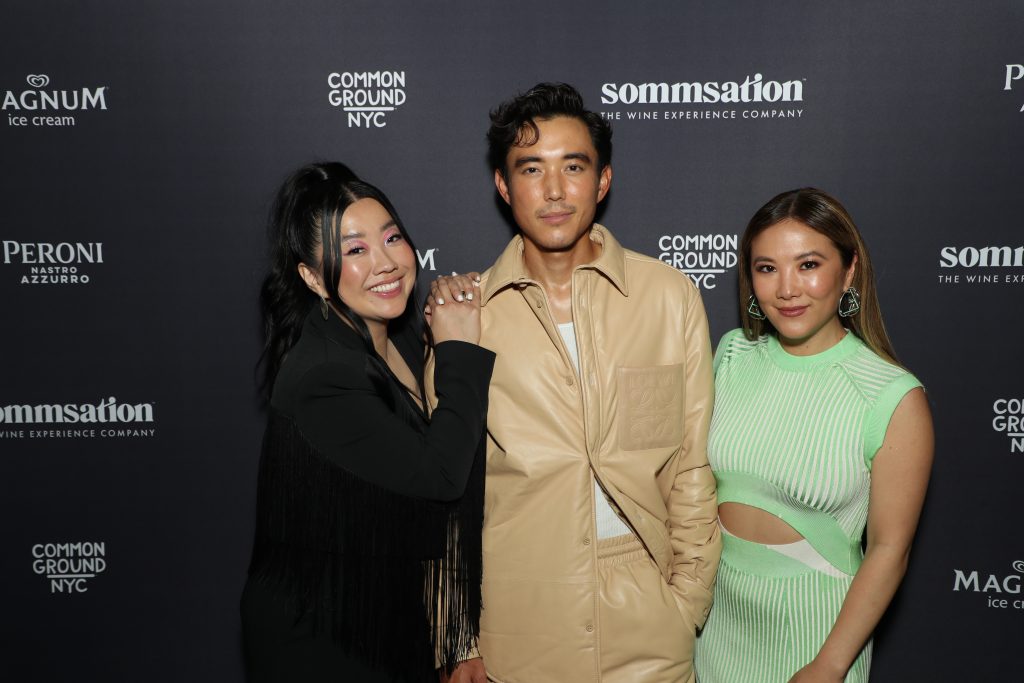 Sherry Cola, Justin H. Min, and Ally Maki posing in front of a sponsor backdrop in promotion of their Tribeca Film Festival film "Shortcomings".