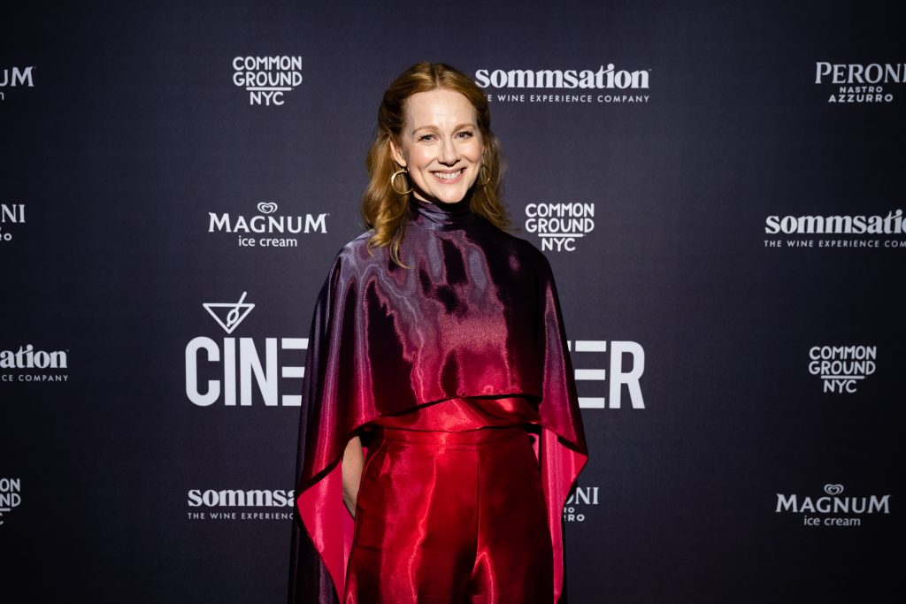 Laura Linney in an absolutely gorgeous purple-to-red ombre gown with over-chest cape. She's posing in front of a sponsor backdrop in promotion of her film "The Miracle Club"