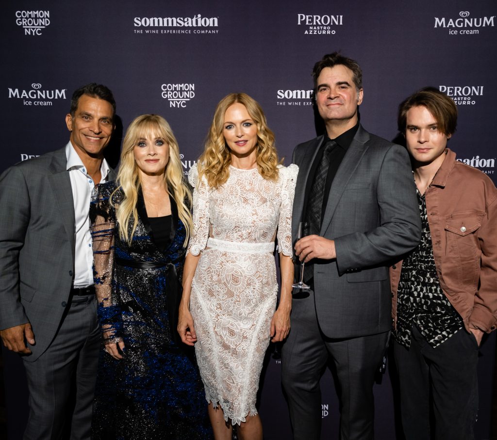 Johnathon Schaech, Barbara Crampton, Heather Graham, Joe Lynch, and Judah Lewis all pose together in a group photo in front of a sponsor backdrop at the premiere event for Suitable Flesh