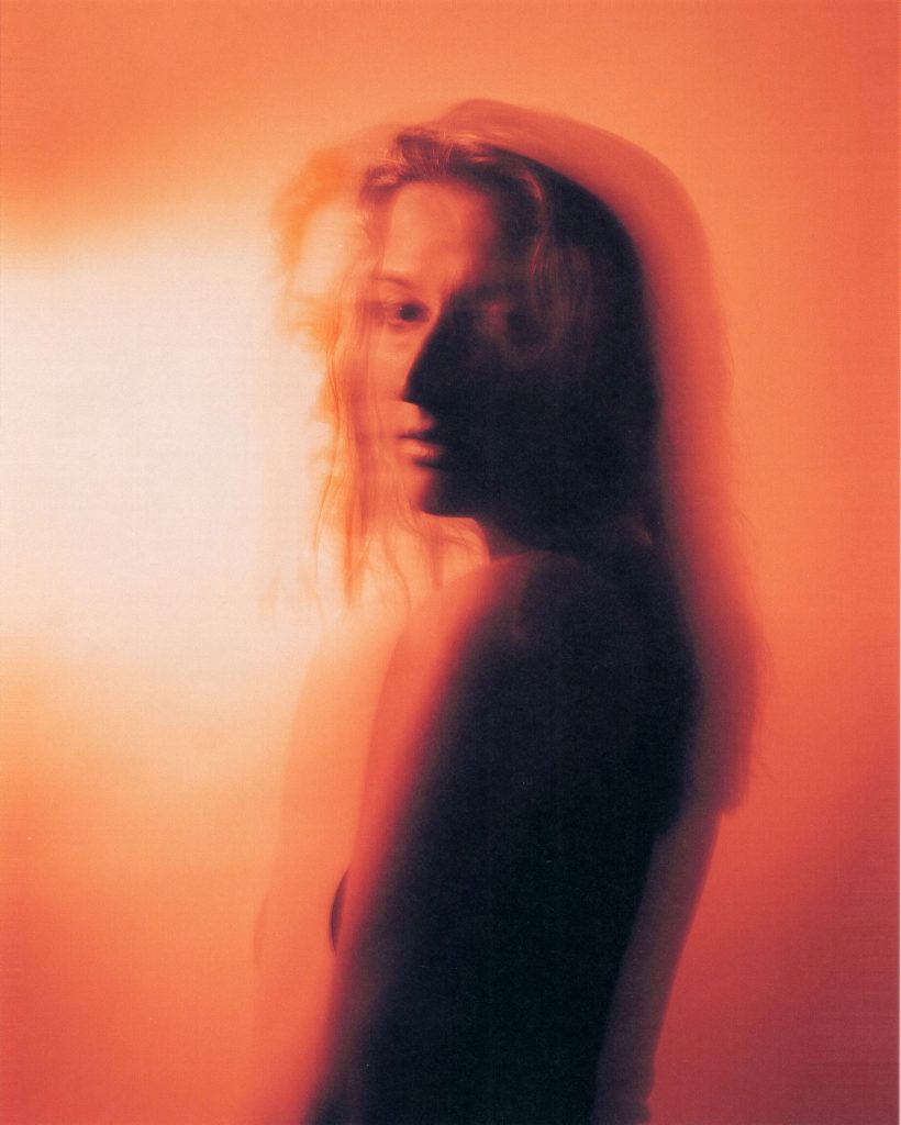 An amber filtered, blurred photo shot of Jenny Kern posing over her shoulder, in promotion of her single "Move On".