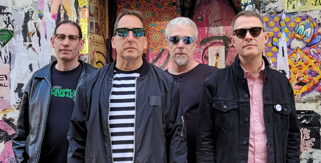 Promotional photo for "Good Girl" which sees The Underbites posing for a band picture. All four members are lined up, all facing the camera, all wearing sunglasses.