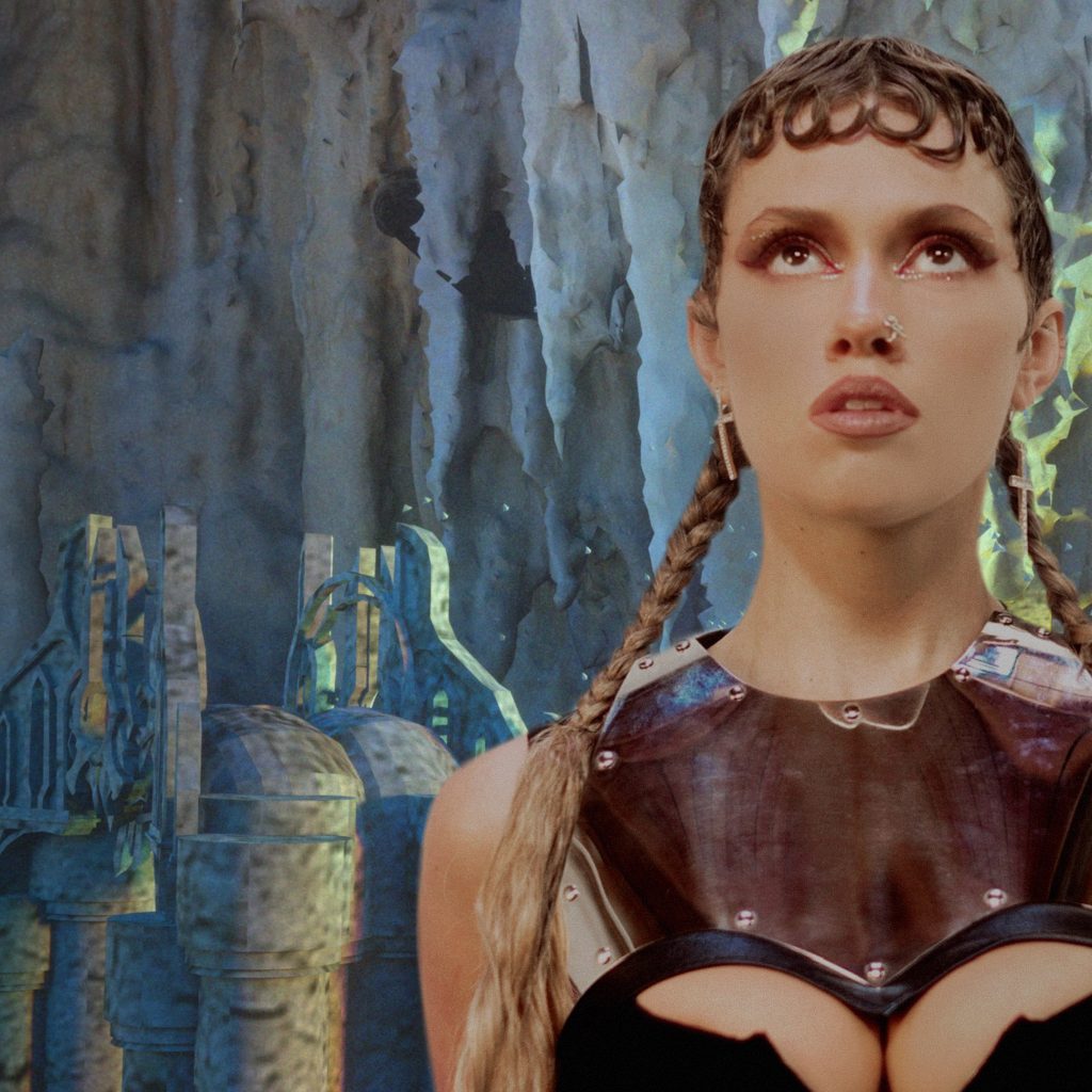 Promotional photo for "Low Jewel" which sees ROWA standing to the right with a grey wall face behind her, dressed up in gladiator-like armour.