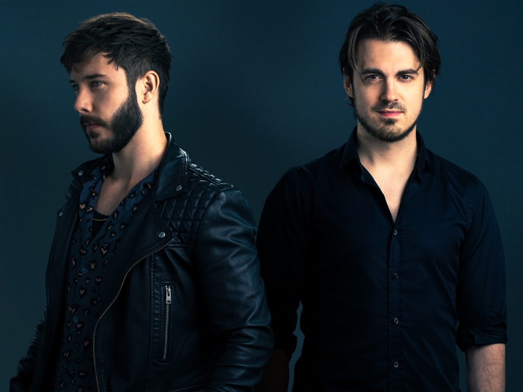 Promotional photo for "Dopamine Junkie" for our exclusive interview which sees Vicetone almost side-to-back as they both wear black and stare longingly,