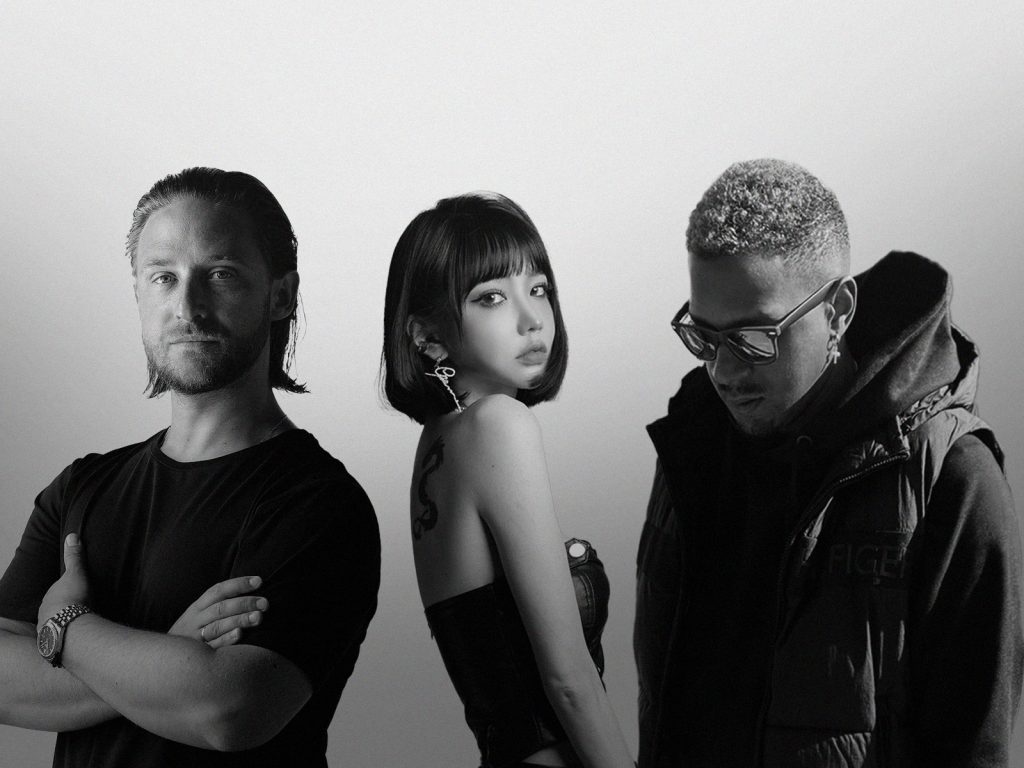A black-and-white Photoshopped press picture for "The Ones We Lost" which sees Brandon Beal on the left wearing a black t-shirt, Lizzy Wang in the middle side-on and wearing a tube dress with her hair in a bob and tucked behind her ear, then HEGEGAARD is on the right looking down and wearing a big thick coat.