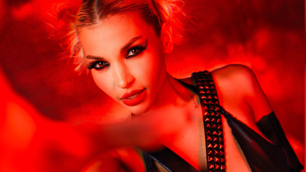 Deena Theodora posing under neon lights in a still image for her single “Sin City.”