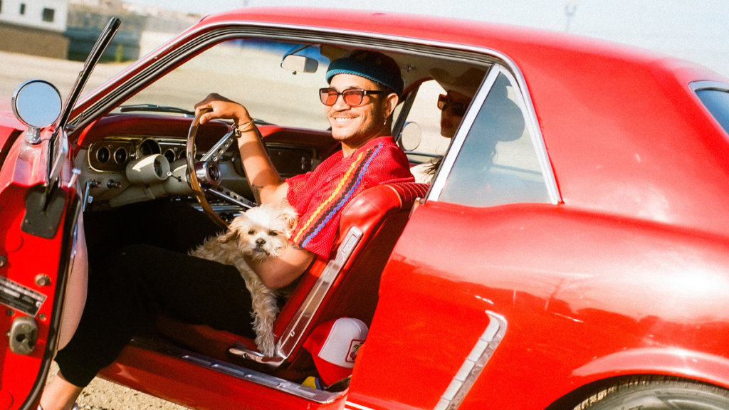 Bryce Vine posing in a red car against a California backdrop for Motel California