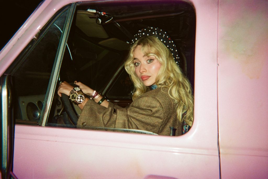 Sabrina Carpenter sat in a pink van for her House Tour music video